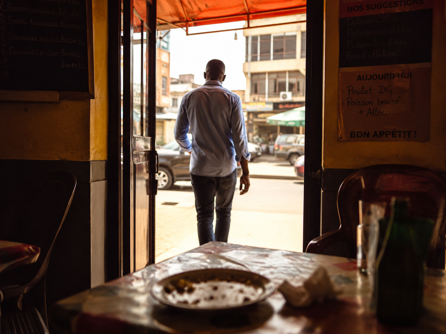 Client quittant un restaurant, vu de dos, table vide au premier plan